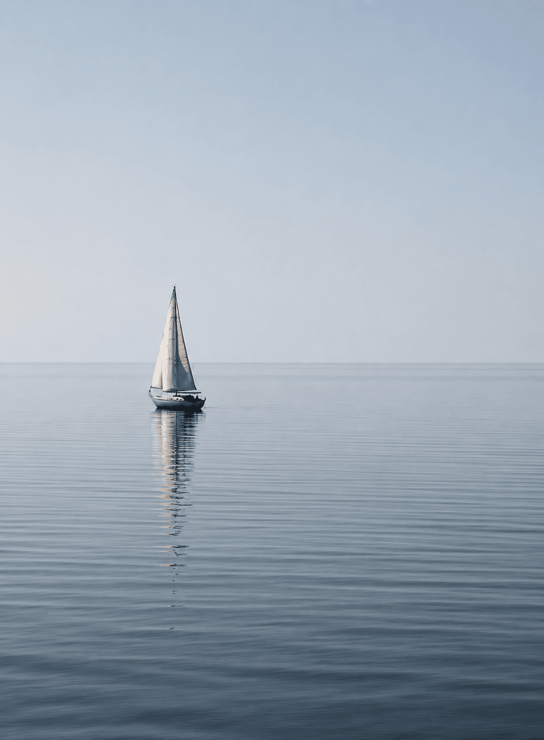 Nautilus Sailing — sailboat reflected in calm blue water