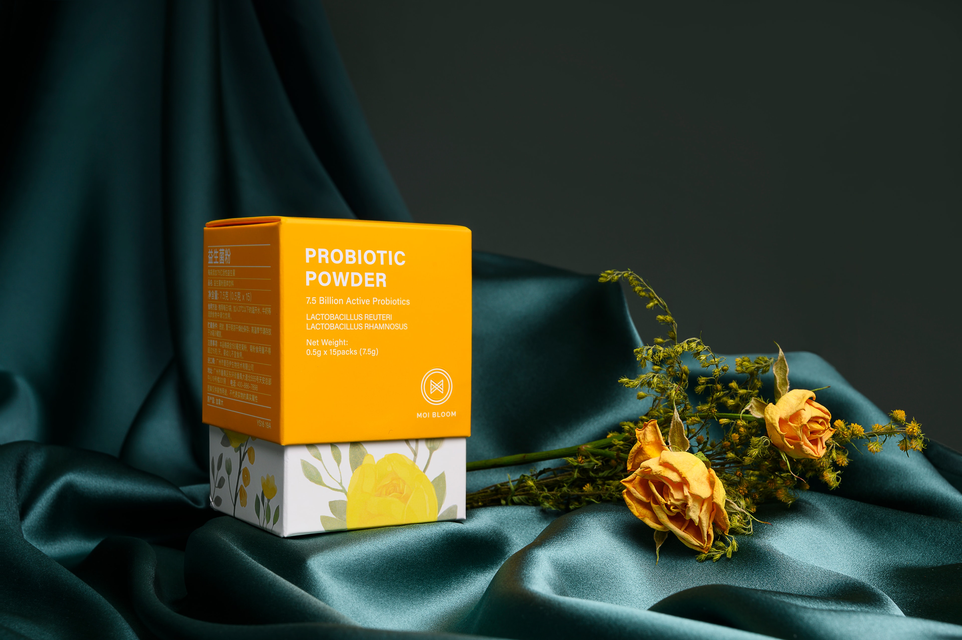 Probiotic powder packaging on teal fabric with yellow roses
