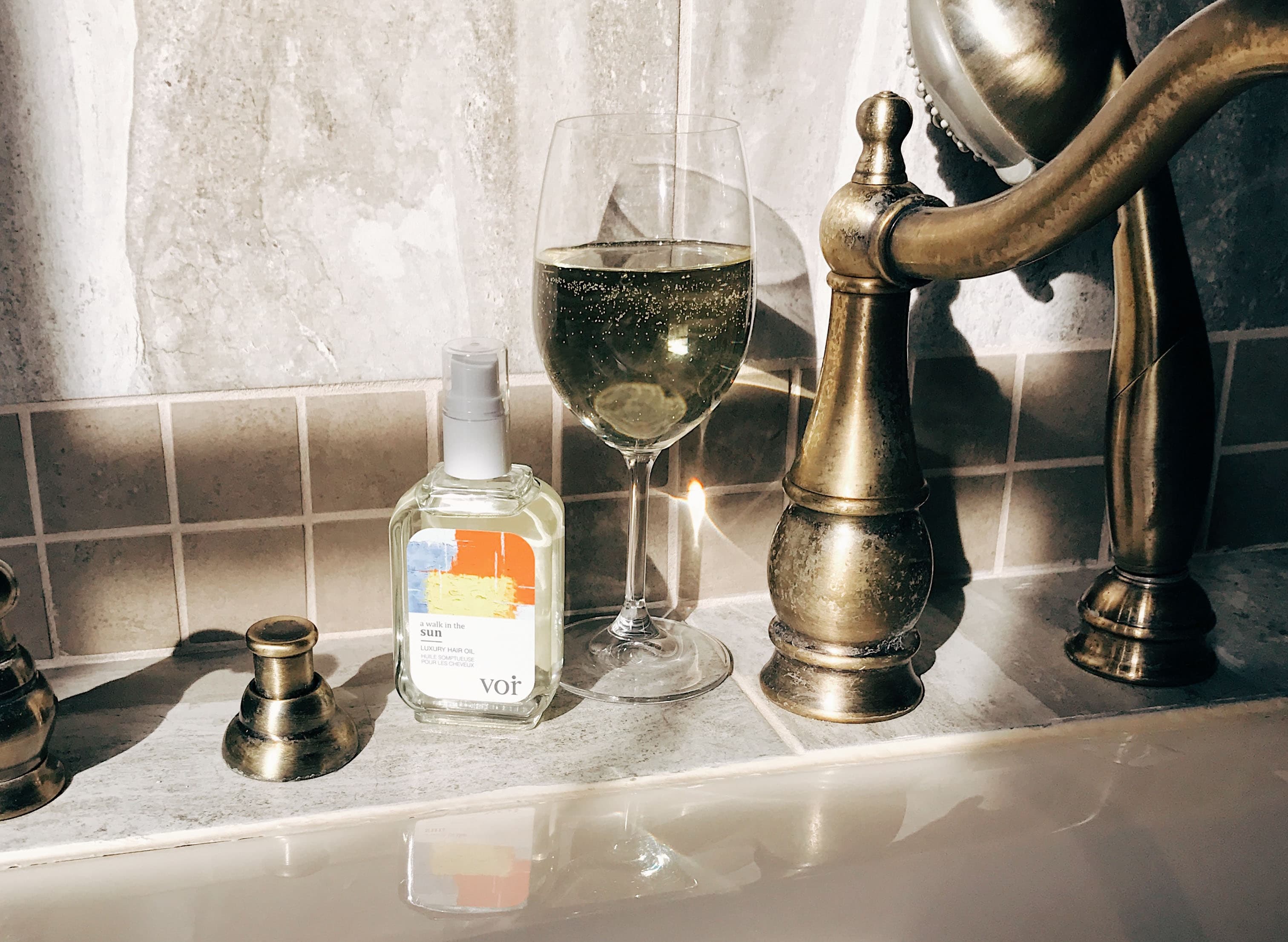 VOIR hair oil beside a brass bathroom faucet
