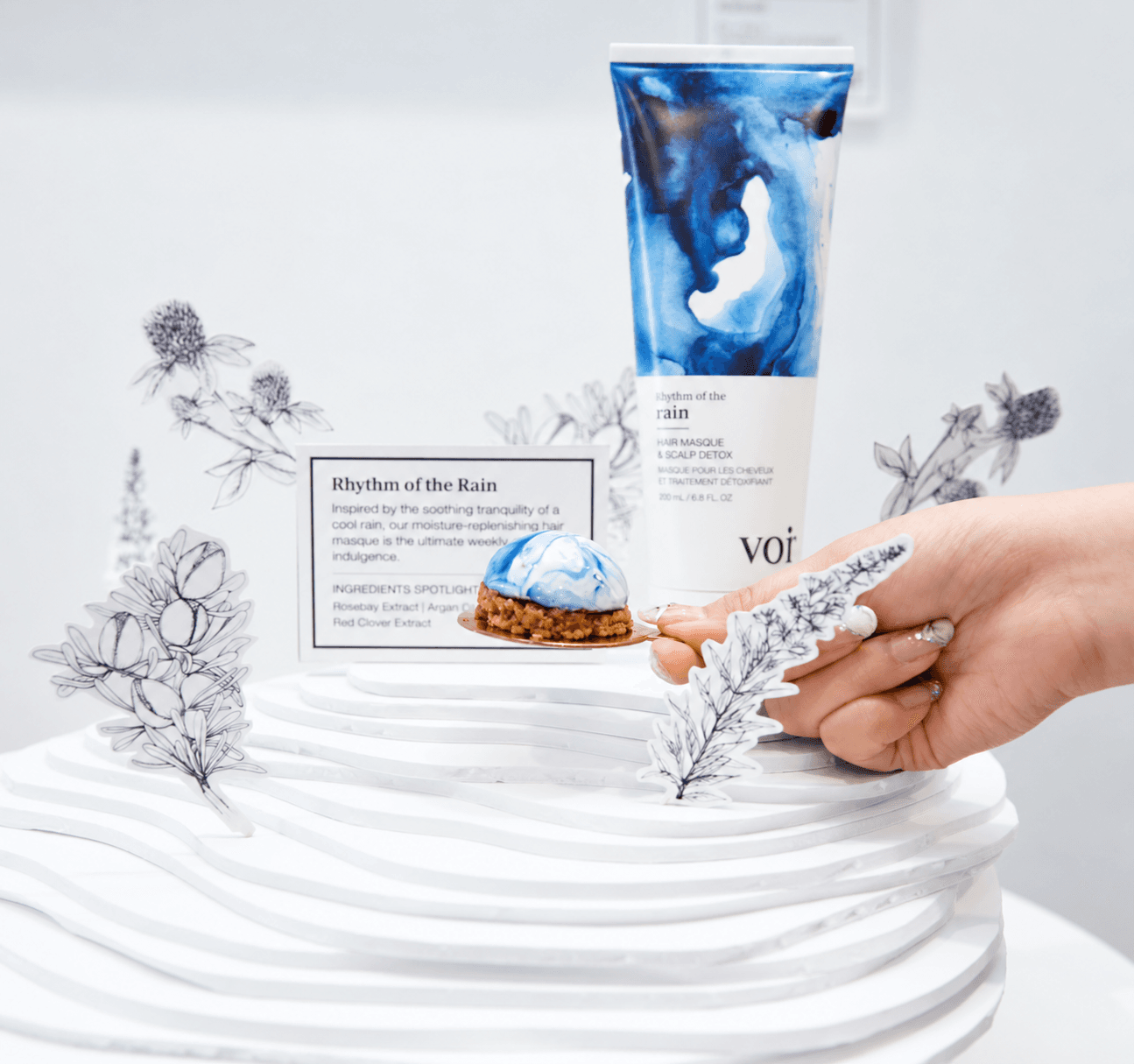 VOIR Rhythm of the Rain hair masque with a blue dessert and floral display