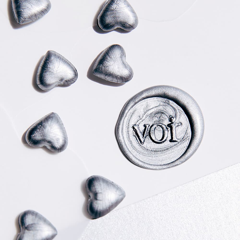 Silver VOIR wax seal surrounded by silver hearts